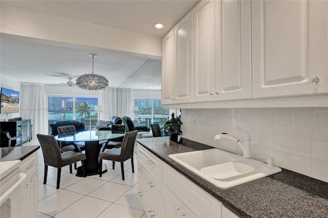kitchen with a sink, white cabinetry, open floor plan, decorative backsplash, and light tile patterned floors