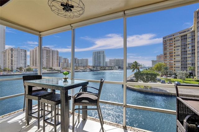 sunroom featuring a view of city, a water view, and a wealth of natural light