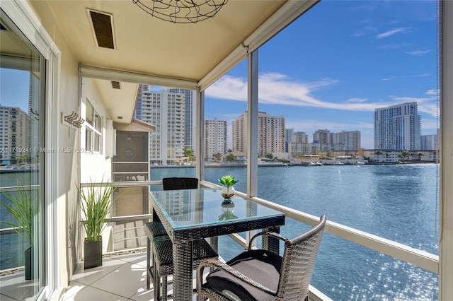 balcony with visible vents, a city view, and a water view