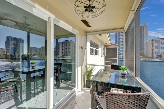 balcony featuring a water view, ceiling fan, and a city view