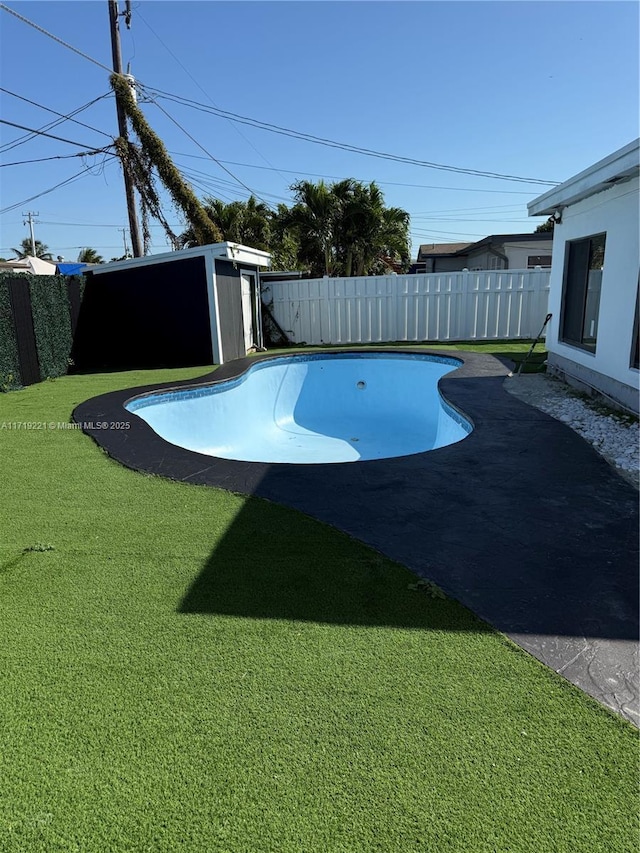 view of pool with a lawn and a storage unit