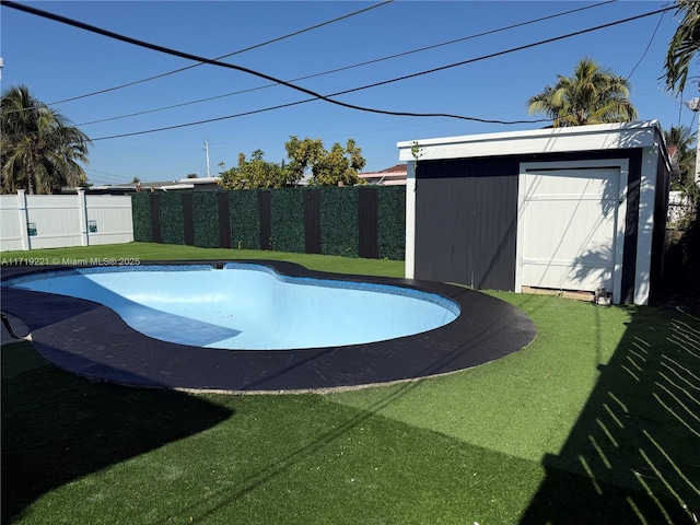 view of swimming pool featuring a lawn and a shed