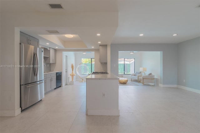 kitchen featuring visible vents, dishwasher, freestanding refrigerator, gray cabinets, and backsplash