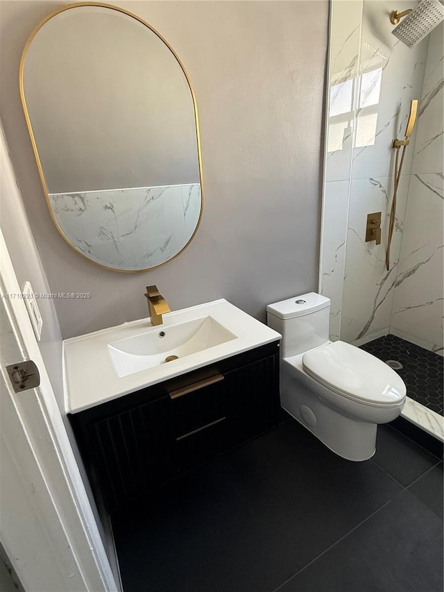 bathroom with toilet, vanity, tile patterned flooring, and tiled shower