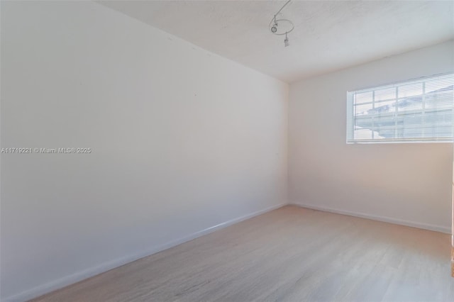 unfurnished room with light wood-type flooring and baseboards