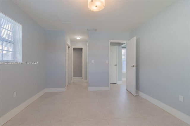 empty room featuring light tile patterned flooring and baseboards