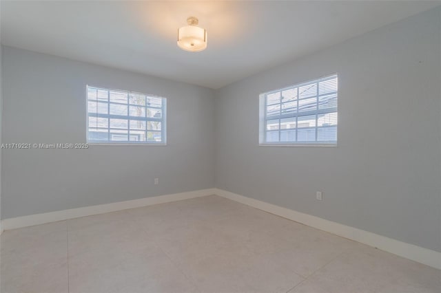 unfurnished room featuring baseboards and a wealth of natural light