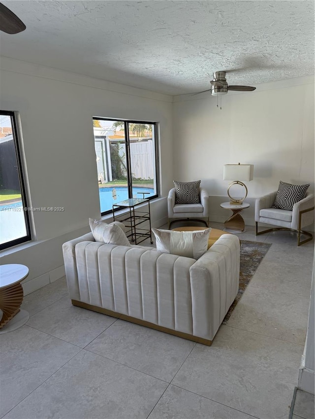 living room featuring a textured ceiling, ceiling fan, and ornamental molding