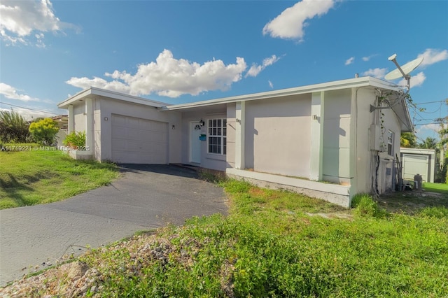 view of front facade featuring a garage, aphalt driveway, a front lawn, and stucco siding