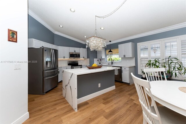 13080 NW 8th Ct, Sunrise, FL 33325 - kitchen with appliances with stainless steel finishes, a chandelier, ornamental molding, backsplash, and a kitchen island