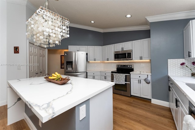 13080 NW 8th Ct, Sunrise, FL 33325 - kitchen with stainless steel appliances, ornamental molding, light wood-style floors, tasteful backsplash, and a chandelier