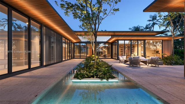 pool at dusk with a patio area and outdoor lounge area