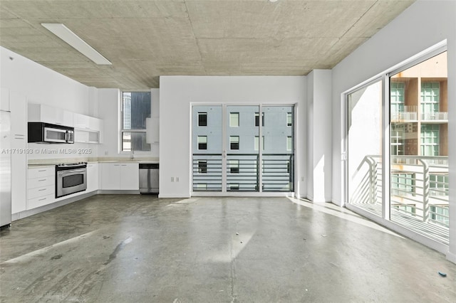 unfurnished living room featuring concrete flooring and a healthy amount of sunlight