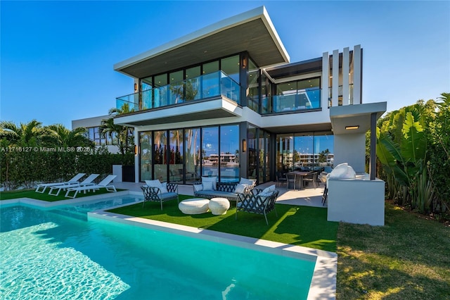 rear view of house with an outdoor living space, a lawn, a balcony, and a patio