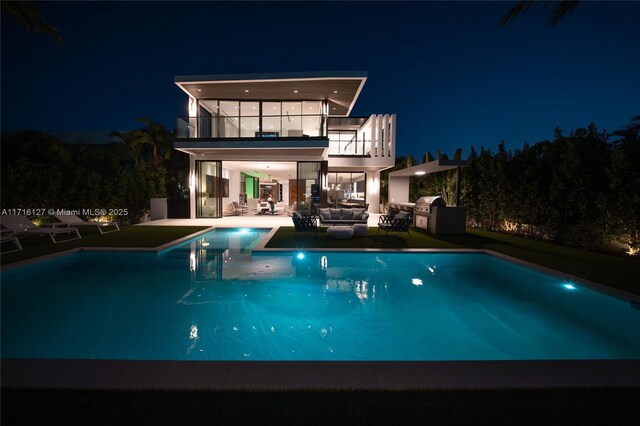 315 N Shore Dr, Miami Beach, FL 33141 - back of house at night with an outdoor pool, a patio, an outdoor hangout area, and a balcony