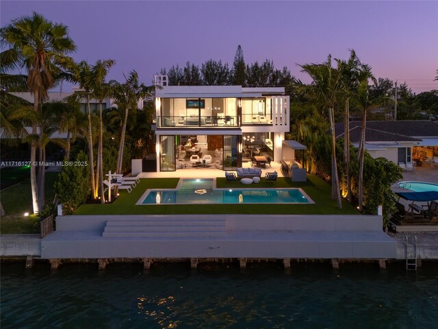 315 N Shore Dr, Miami Beach, FL 33141 - back of property at dusk with a patio area, outdoor lounge area, a water view, and a balcony