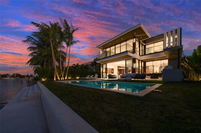 315 N Shore Dr, Miami Beach, FL 33141 - back of house at night with an outdoor pool, an outdoor living space, a patio, and a balcony