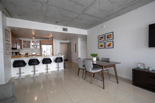 kitchen with light tile patterned floors, kitchen peninsula, a breakfast bar area, and appliances with stainless steel finishes