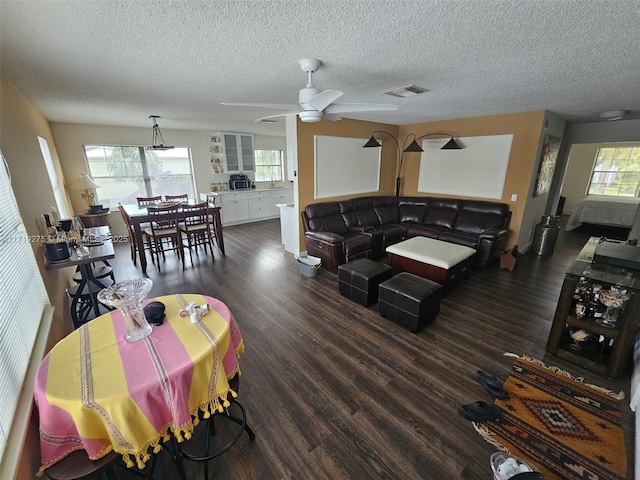 living room with ceiling fan, dark wood-type flooring, and a textured ceiling