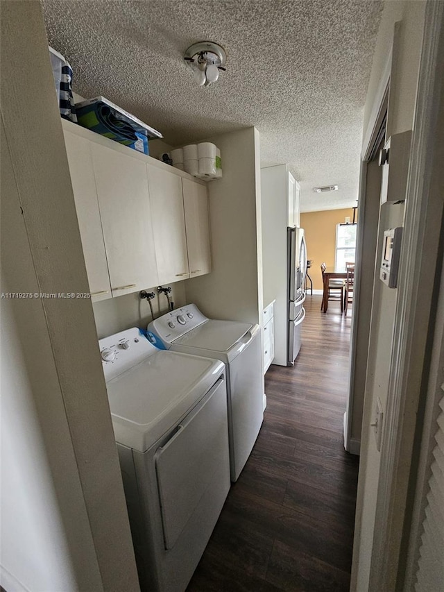 laundry room with cabinets, dark hardwood / wood-style floors, washing machine and dryer, and a textured ceiling