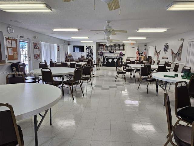 dining area featuring ceiling fan and a textured ceiling