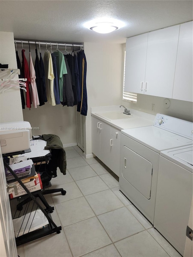 laundry area with cabinets, a textured ceiling, sink, washer and dryer, and light tile patterned floors