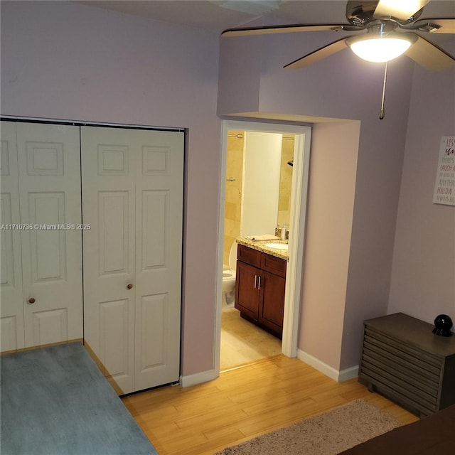 bedroom with ceiling fan, light wood-type flooring, ensuite bathroom, and a closet