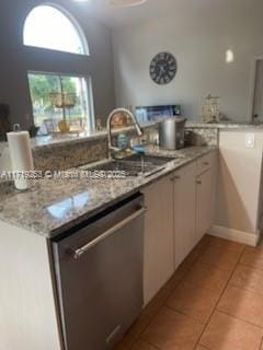 kitchen featuring dishwasher, white cabinets, sink, light stone countertops, and light tile patterned floors