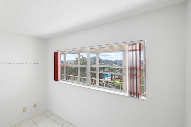 tiled empty room featuring a healthy amount of sunlight and a textured ceiling