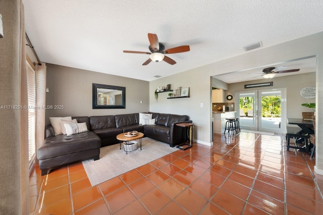 living room featuring tile patterned flooring, ceiling fan, and a textured ceiling