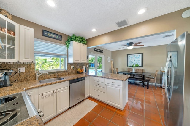 kitchen with kitchen peninsula, appliances with stainless steel finishes, ceiling fan, sink, and white cabinets