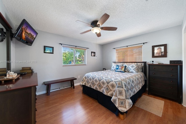 bedroom with ceiling fan, wood-type flooring, and a textured ceiling