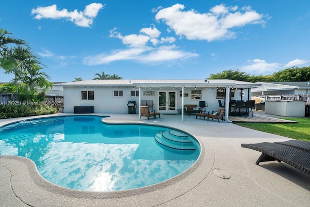 view of pool with french doors, an outdoor kitchen, an outdoor hangout area, a grill, and a patio area