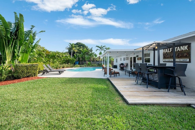 view of swimming pool featuring a lawn, exterior bar, and a deck