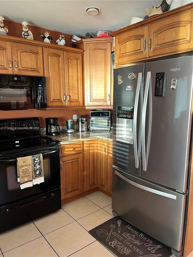 kitchen featuring black appliances, light tile patterned flooring, and light stone countertops