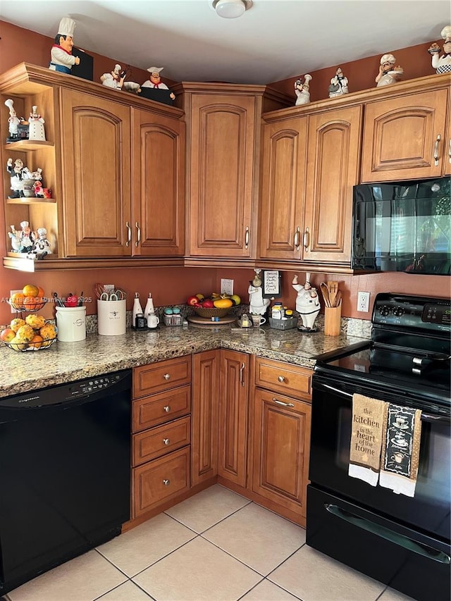 kitchen with dark stone countertops, light tile patterned flooring, and black appliances