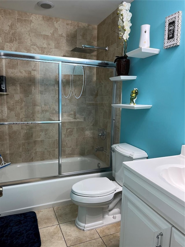 full bathroom with tile patterned flooring, vanity, bath / shower combo with glass door, and toilet