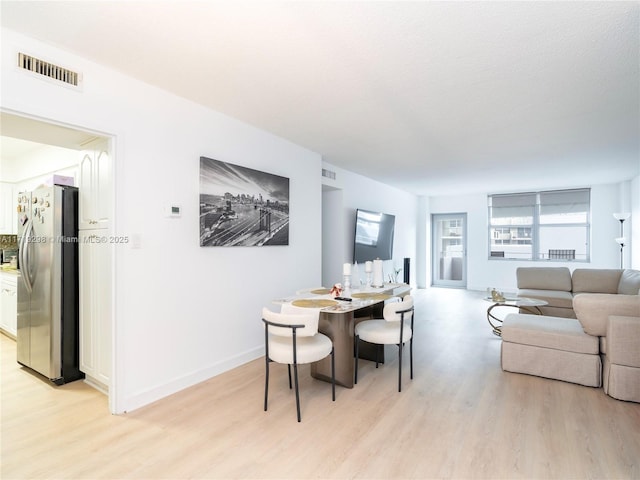 dining space featuring light wood finished floors, visible vents, and baseboards
