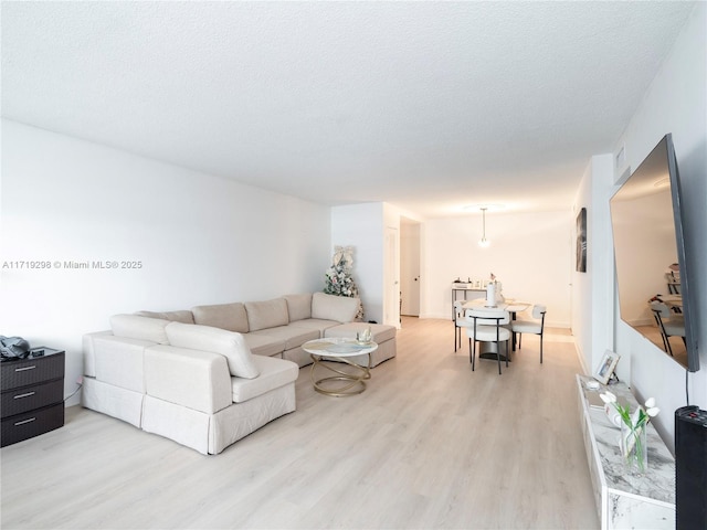 living room with visible vents, light wood-style flooring, and a textured ceiling