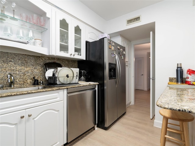 kitchen with light wood-style floors, glass insert cabinets, white cabinetry, visible vents, and appliances with stainless steel finishes