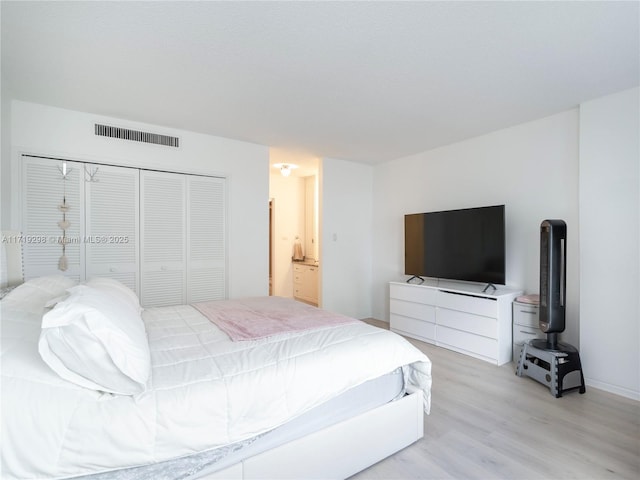 bedroom with visible vents, light wood-type flooring, and a closet