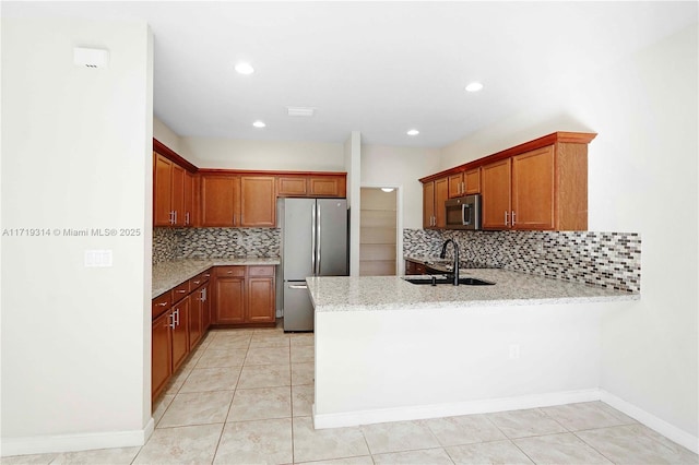 kitchen featuring sink, tasteful backsplash, kitchen peninsula, light tile patterned floors, and appliances with stainless steel finishes