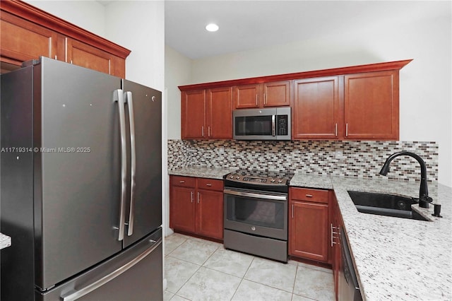 kitchen featuring sink, decorative backsplash, light tile patterned floors, light stone countertops, and appliances with stainless steel finishes