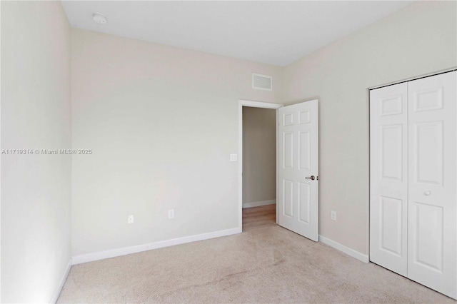 unfurnished bedroom featuring light carpet and a closet