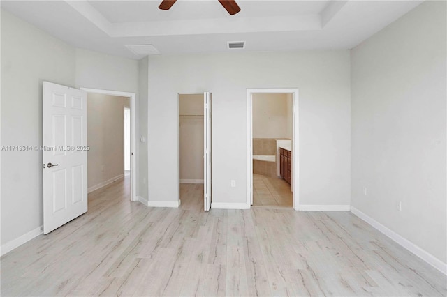 unfurnished bedroom with a walk in closet, ensuite bathroom, ceiling fan, light hardwood / wood-style floors, and a closet