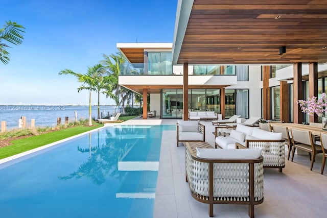 view of pool featuring outdoor lounge area, a patio area, and a water view