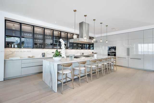 kitchen featuring island exhaust hood, a spacious island, and hanging light fixtures