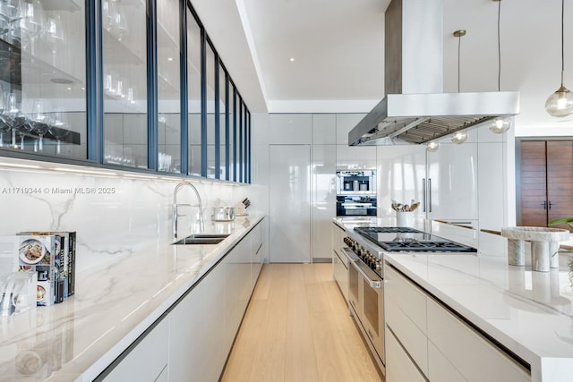 kitchen with white cabinetry, sink, decorative light fixtures, island range hood, and stainless steel stove