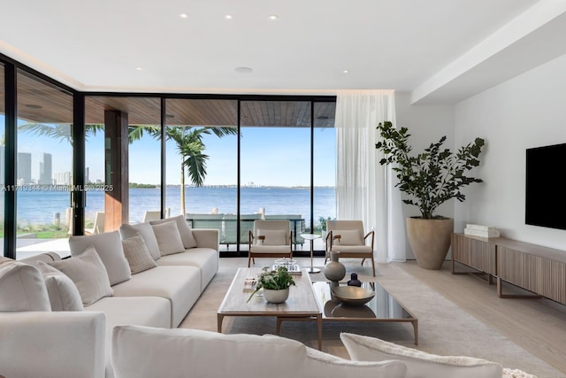 living room featuring a water view, floor to ceiling windows, and light hardwood / wood-style floors