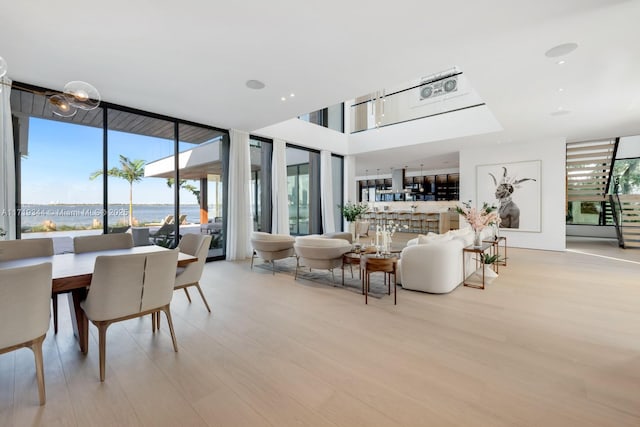 living room featuring expansive windows, light hardwood / wood-style flooring, and a water view